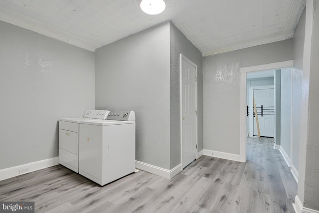 clothes washing area with washing machine and clothes dryer, light wood-type flooring, and baseboards
