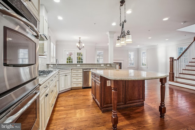 kitchen featuring a sink, ornamental molding, a breakfast bar area, a chandelier, and appliances with stainless steel finishes