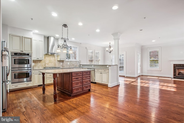 kitchen featuring a breakfast bar, open floor plan, wall chimney exhaust hood, tasteful backsplash, and appliances with stainless steel finishes