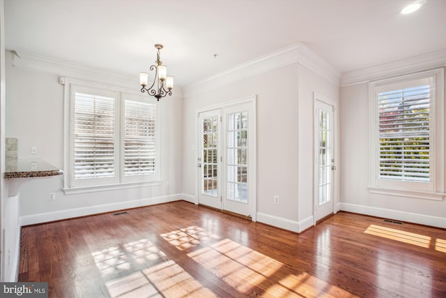 unfurnished dining area with crown molding, a notable chandelier, baseboards, and wood finished floors