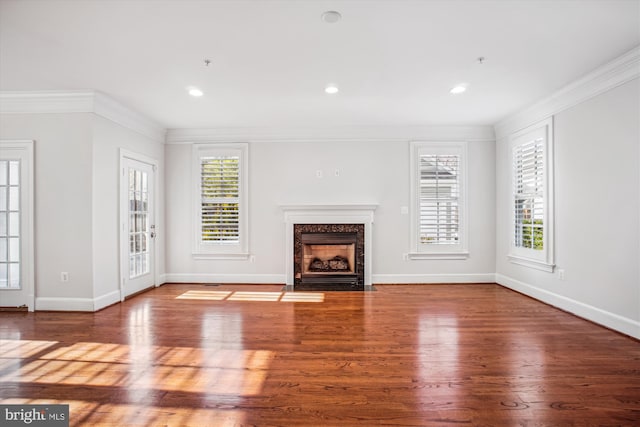 unfurnished living room featuring crown molding, a wealth of natural light, and wood finished floors