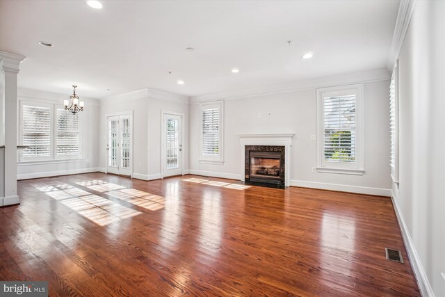 unfurnished living room with an inviting chandelier, a fireplace, visible vents, baseboards, and ornamental molding
