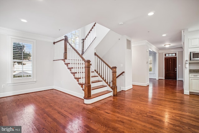 entryway featuring crown molding, visible vents, wood finished floors, and baseboards