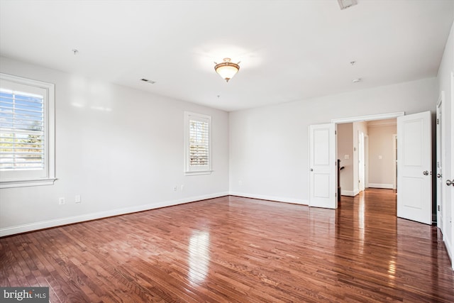 spare room with baseboards, visible vents, and wood finished floors