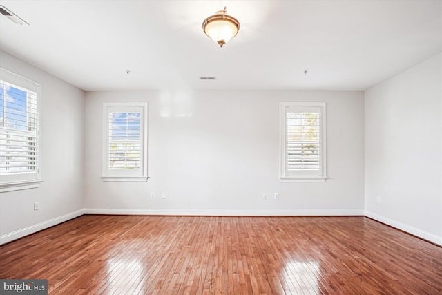 spare room featuring visible vents, baseboards, and wood-type flooring