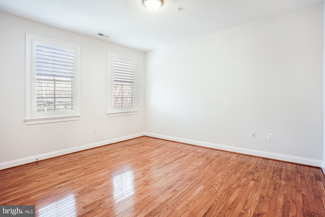 unfurnished room featuring baseboards, visible vents, and wood finished floors