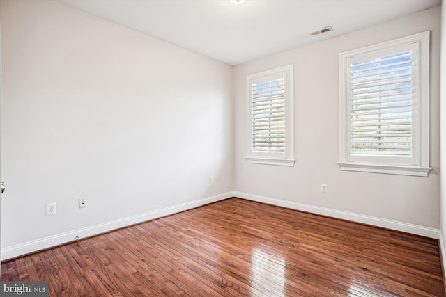 spare room with baseboards, wood-type flooring, and plenty of natural light