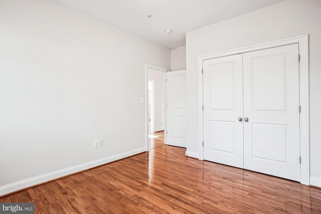 unfurnished bedroom featuring baseboards, a closet, and wood finished floors