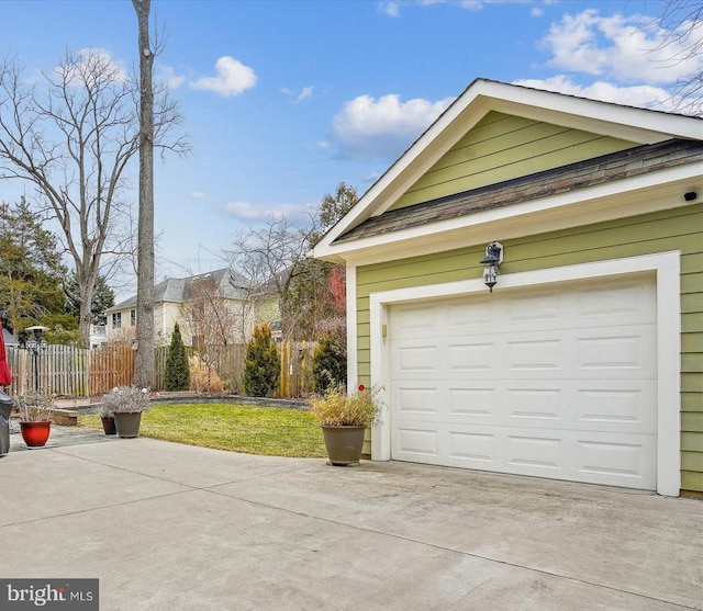 garage featuring concrete driveway and fence