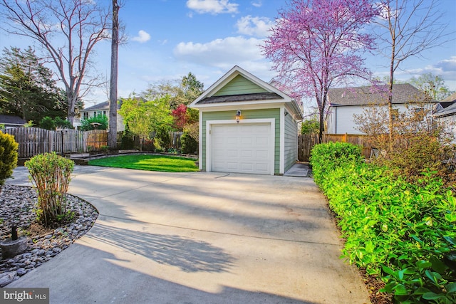 garage with concrete driveway and fence