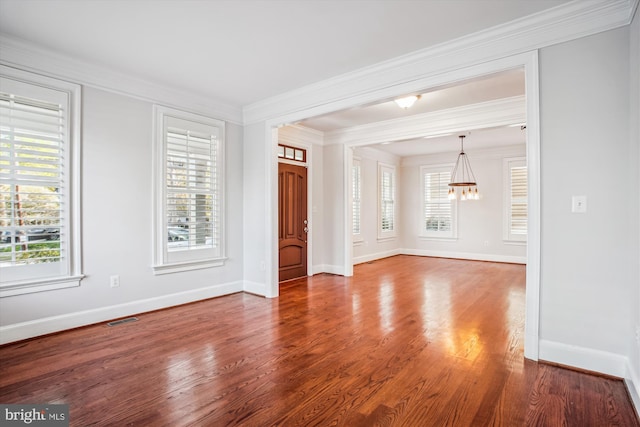 unfurnished living room with a chandelier, ornamental molding, visible vents, and wood finished floors