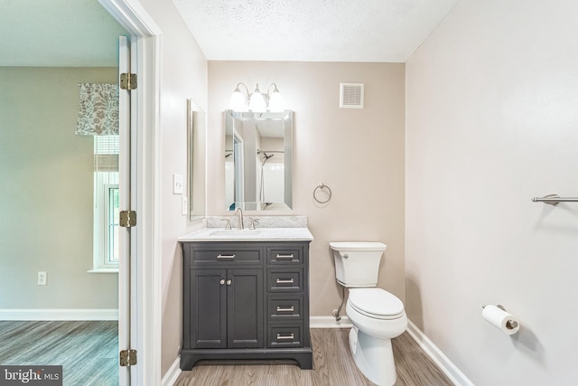 bathroom featuring toilet, baseboards, visible vents, vanity, and wood finished floors
