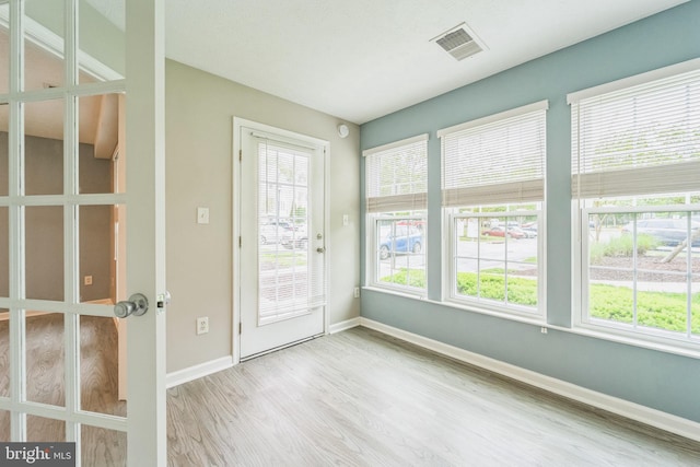 doorway with visible vents, wood finished floors, and baseboards