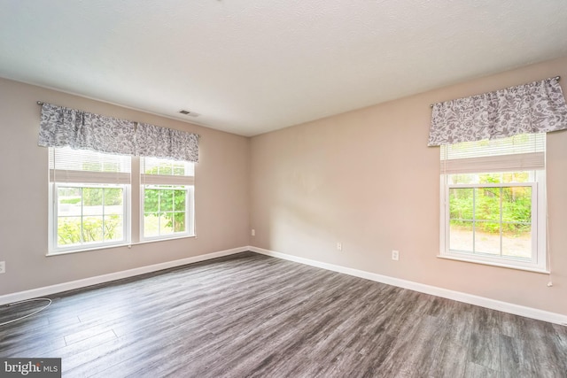 spare room with dark wood-type flooring, baseboards, and visible vents