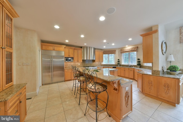 1389 Lamplighter Cir, Gwynedd, PA 19436 - kitchen featuring built in appliances, a kitchen island, a sink, wall chimney exhaust hood, and a breakfast bar area