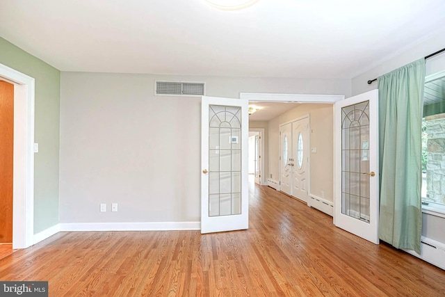entryway with baseboard heating, light wood finished floors, french doors, and plenty of natural light