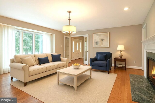 living area with a fireplace with flush hearth, wood finished floors, baseboards, and recessed lighting