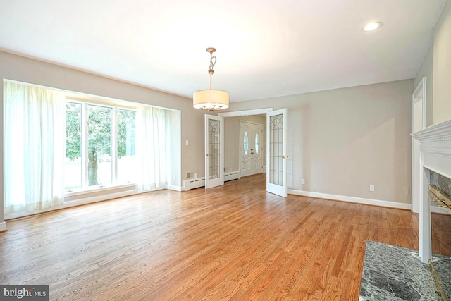 unfurnished living room with baseboards, light wood finished floors, a fireplace with flush hearth, french doors, and recessed lighting