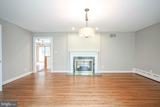 unfurnished living room featuring light wood finished floors, recessed lighting, baseboards, a fireplace, and a baseboard radiator