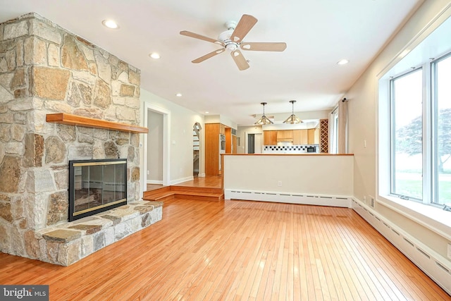 unfurnished living room featuring baseboard heating, light wood finished floors, a fireplace, a ceiling fan, and recessed lighting