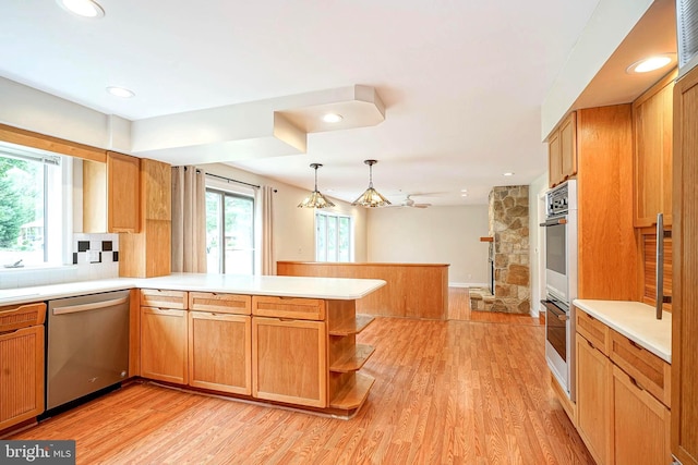 kitchen featuring appliances with stainless steel finishes, a peninsula, light countertops, light wood-style flooring, and recessed lighting