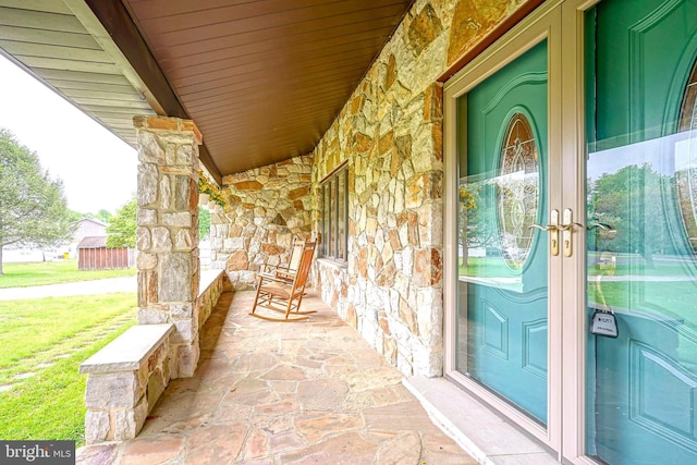 property entrance with stone siding and a porch