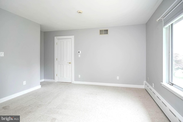 carpeted spare room with a baseboard radiator, plenty of natural light, and baseboards