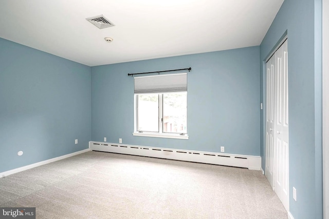unfurnished bedroom featuring baseboard heating, carpet, a closet, and baseboards