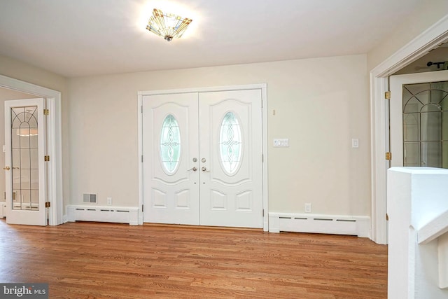 foyer entrance with a baseboard radiator, baseboard heating, wood finished floors, and french doors