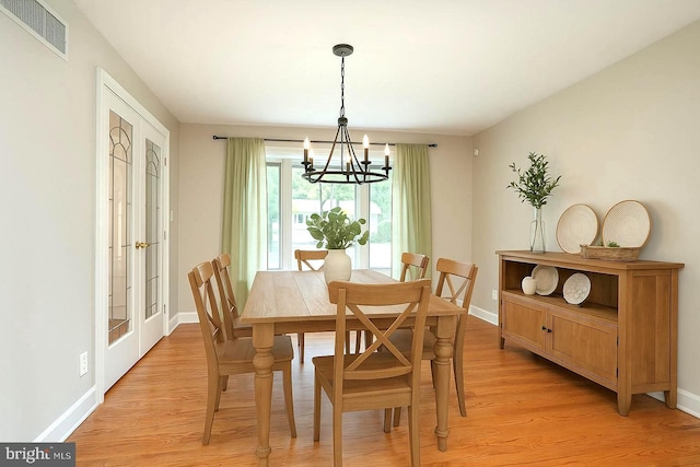 dining room with a chandelier, light wood finished floors, and baseboards