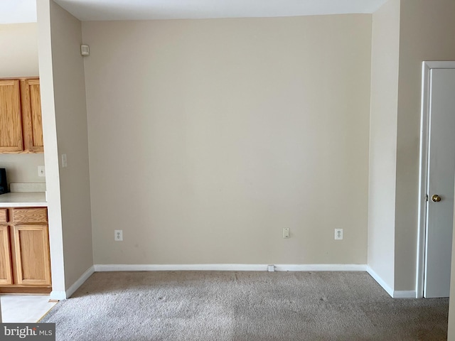 unfurnished room featuring light colored carpet and baseboards