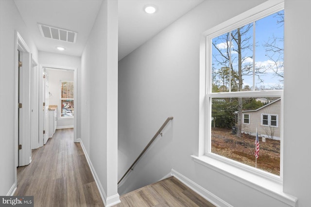 corridor with wood finished floors, plenty of natural light, an upstairs landing, and visible vents