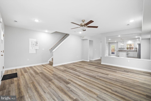 unfurnished living room featuring light wood-type flooring, stairway, ceiling fan, and recessed lighting