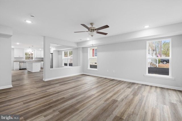unfurnished living room featuring wood finished floors, baseboards, ceiling fan, and recessed lighting