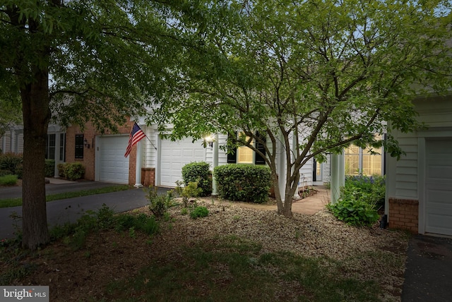 view of front of home featuring brick siding, an attached garage, and driveway