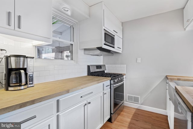6526 N Capitol St NW, Washington, DC 20012 - kitchen with stainless steel appliances, baseboards, wood counters, and decorative backsplash