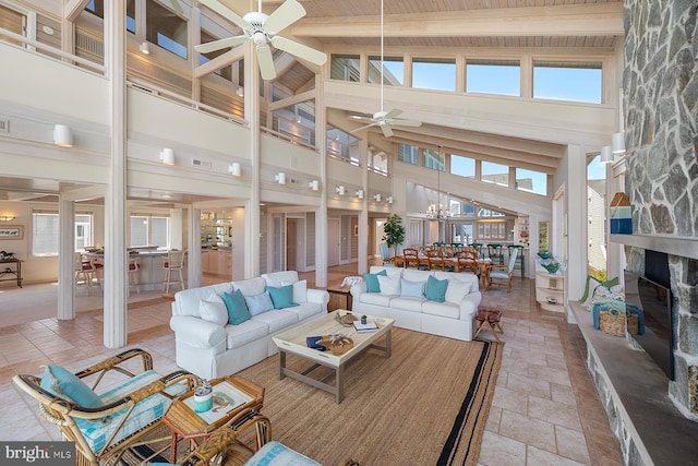 40113 Owens Ct, Fenwick Island, DE 19944 - living room with ceiling fan with notable chandelier, a high ceiling, a fireplace, stone tile flooring, and beamed ceiling