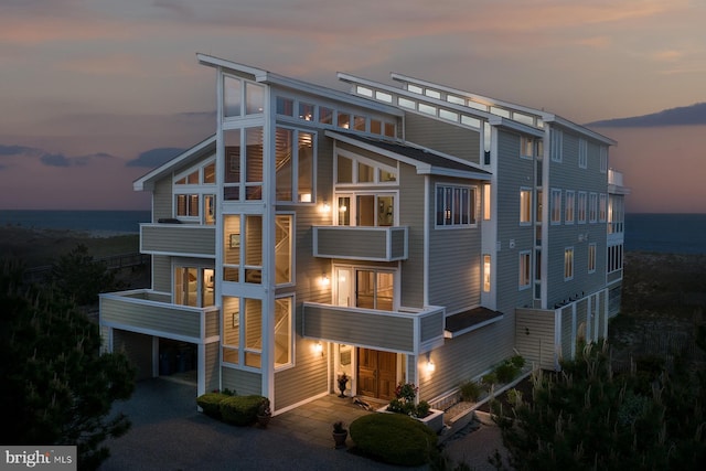 40113 Owens Ct, Fenwick Island, DE 19944 - back of house at dusk featuring a water view, driveway, and a balcony