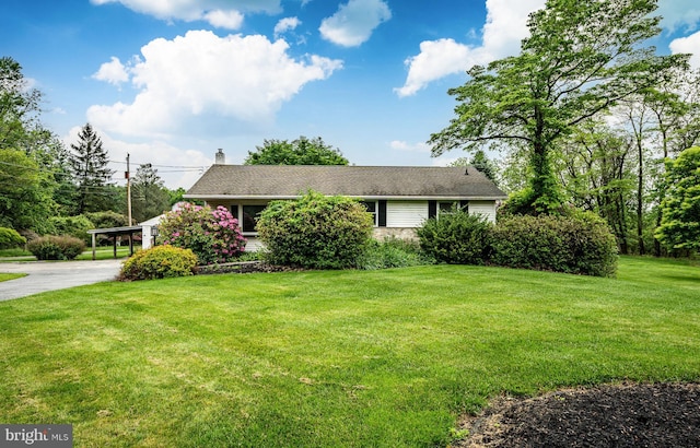 view of front of home featuring a chimney, a front lawn, and driveway