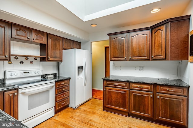 kitchen with white appliances, light wood-type flooring, dark stone countertops, and recessed lighting
