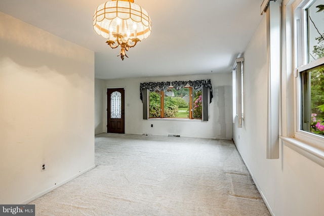 unfurnished room featuring carpet, a chandelier, and baseboards