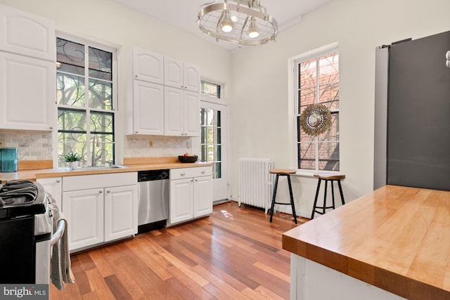 2133 Bolton St, Baltimore, MD 21217 - kitchen featuring stainless steel appliances, radiator heating unit, light wood finished floors, and decorative backsplash