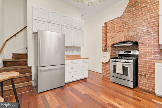 2133 Bolton St, Baltimore, MD 21217 - kitchen featuring appliances with stainless steel finishes, light wood-type flooring, white cabinets, backsplash, and wooden counters