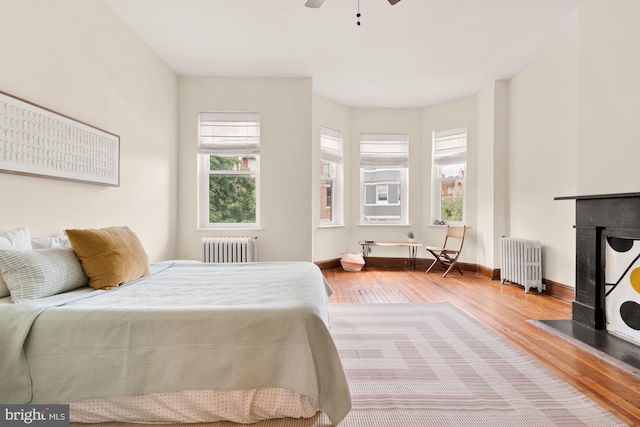 2133 Bolton St, Baltimore, MD 21217 - bedroom with radiator, wood finished floors, a fireplace, and baseboards