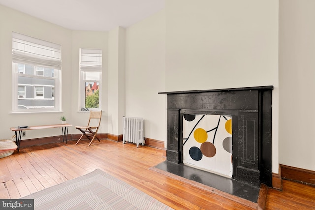 2133 Bolton St, Baltimore, MD 21217 - detailed view of radiator, wood finished floors, a fireplace with flush hearth, and baseboards
