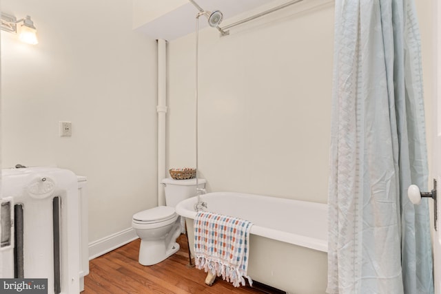2133 Bolton St, Baltimore, MD 21217 - bathroom with a freestanding tub, toilet, wood finished floors, baseboards, and radiator