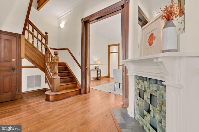 2133 Bolton St, Baltimore, MD 21217 - entrance foyer with ornamental molding, stairway, wood-type flooring, and a stone fireplace