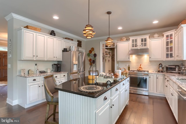 kitchen with white cabinets, appliances with stainless steel finishes, a center island, and tasteful backsplash