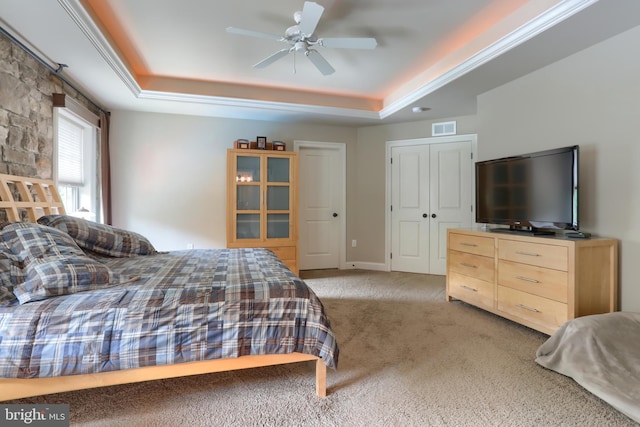 bedroom featuring light colored carpet, a raised ceiling, ceiling fan, and visible vents