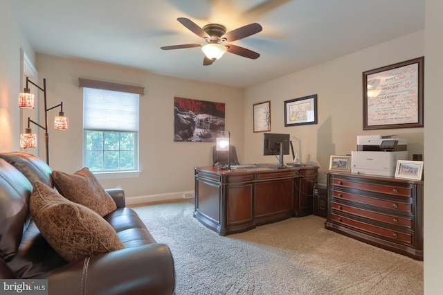 office featuring a ceiling fan, light carpet, and baseboards